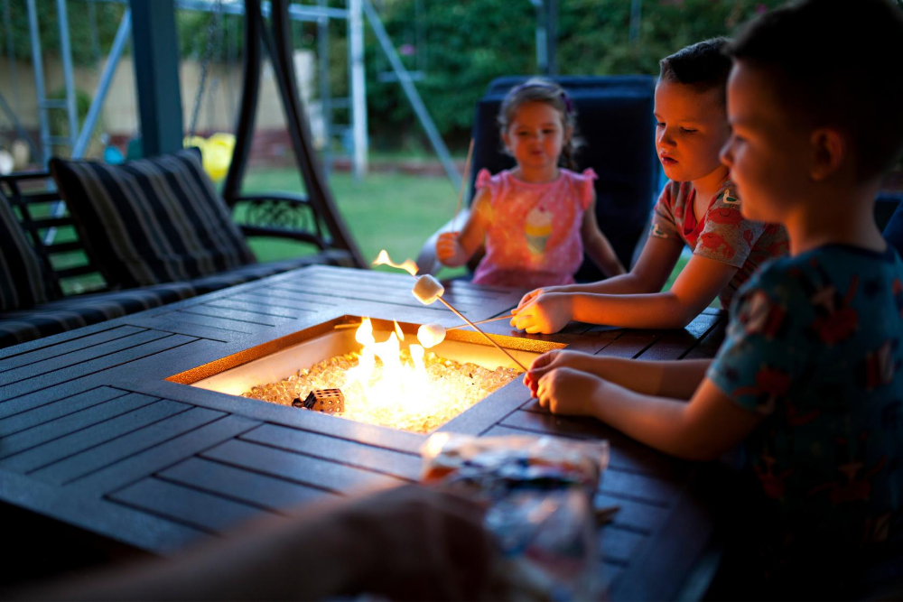 children roast marshmallows over a fire pit in their backyard