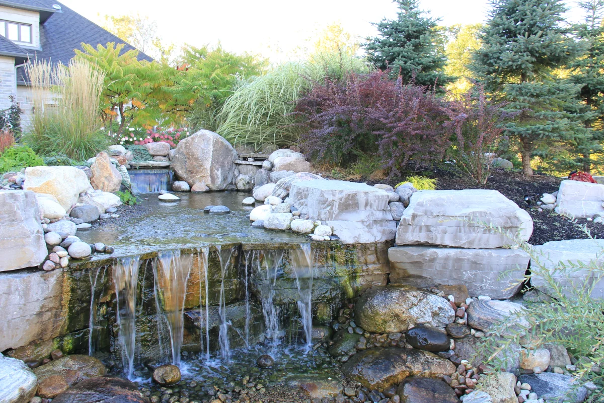 Osmond Daly natural-stone waterfall surrounded by mature planting