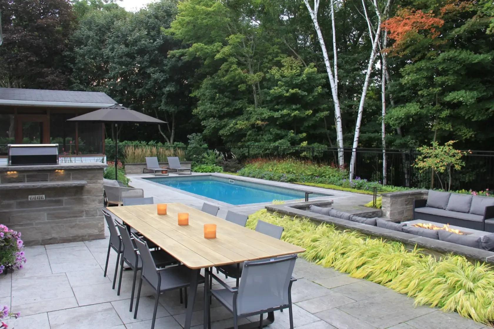 Large-format paved patio with an outdoor dining table beside the pool