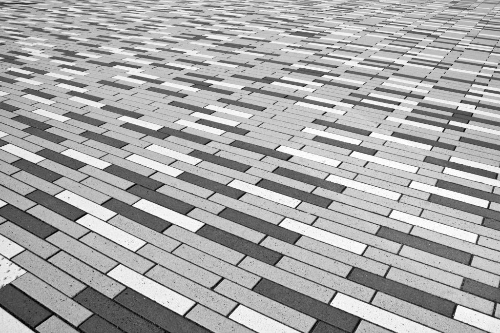 Driveway designed with interlocking stone in long, linear patterns varying in shades of grey.