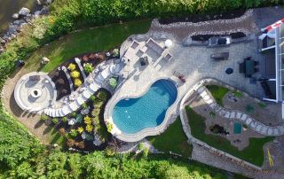 aerial view of beautifully landscaped back yard with stone work and inground pool