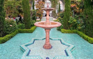 An exotic water structure stands in the middle of a lush garden landscape