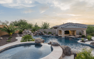 Landscape of a home with pool and spa with decorative boulders