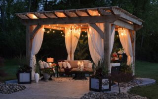 Backyard gazebo set up at night with lights and beautiful patio furniture on a manicured lawn