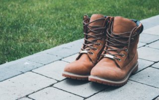 construction boots on an interlock stone pathway next to a manicured lawn