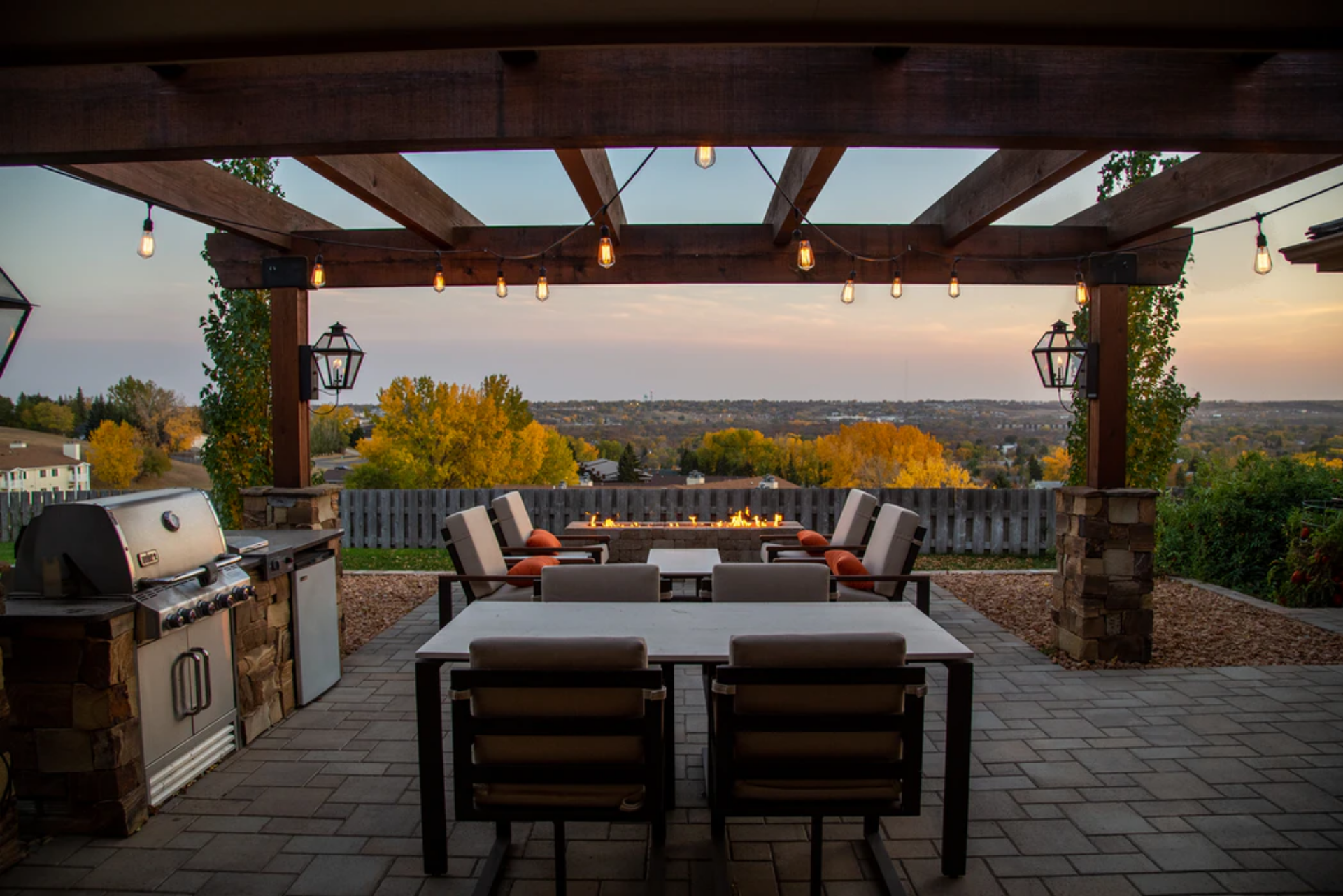 view of backyard home landscape under pergola with outdoor kitchen and dinning area