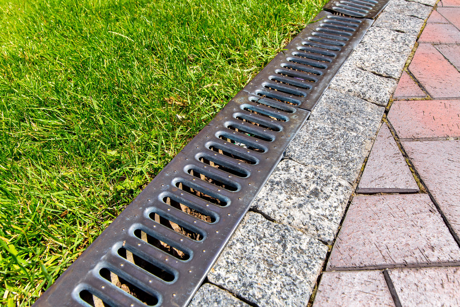 Example of a drainage system along the interlock and grass